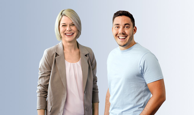 Eine Frau im Blazer und ein Mann im T-Shirt lächeln gemeinsam vor neutralem Hintergrund.
